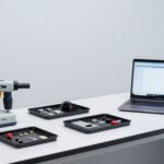 Bàn thử nghiệm điện tử với máy XRF cầm tay, các mẫu nhỏ trong khay, mảnh dây cáp và laptop hiển thị phổ trống — ảnh bìa bài XRF sàng lọc RoHS